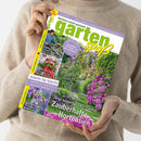 Eine hell gekleidete Person hält eine Ausgabe der Zeitschrift „gartenspaß“ in zwei Händen, Titelthema „Zauberhafte Hortensien“. Das farbige Cover zeigt einen sommerlichen Gartenweg mit violett blühenden Hortensien, grüner Laubhecke und Rosenbogen. Weitere sichtbare Schlagzeilen: „Schritt für Schritt“, „Bienenmagnete“, „Bunter Blickfang“, „Gärtnern leicht gemacht“ und „Gestalten mit Rank- & Rosenbögen“.