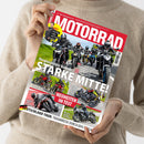 Magazincover „MOTORRAD“ mit rotem Titelbalken und weißer Schrift, gezeigt in den Händen einer Person in beigefarbenem Pullover. Auf dem Cover fünf Motorräder in Fahrt auf einer Landstraße, Überschrift „Vergleichstest Nakeds – STARKE MITTE!“. Weitere sichtbare Textelemente: „NEUHEITEN IM TEST“, „Honda CB 750 Hornet“, „Kawasaki Z650“, „Suzuki GSX-8S“, „Yamaha MT-07“, „Triumph Speed Triple 1200“, „Deutschland-Tour: Traumreise durch den Schwarzwald“.