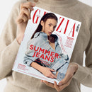 Titelblatt der Zeitschrift „Grazia“, gehalten von einer Person in beigem Strickpullover vor neutralem Hintergrund. Auf dem Cover ist eine weibliche Person in hellblauer Jeansjacke und Jeans zu sehen, mit rotem Titeltext „SUMMER-JEANS – Die coolsten Trends der Saison“ sowie weiteren Aufschriften zu den Themen „Wedding-Special“, „Double Denim“, „Exklusiv“ und Modetrends.