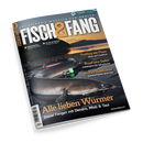 Schräg fotografiertes, glänzendes Angelmagazin „FISCH&FANG“ mit dem Untertitel „Das Erlebnis-Magazin für Angler“ vor schwarzem Hintergrund; auf dem Cover liegt ein großer silbrig-grauer Fisch mit rotem Köder und grünem Zubehör. Sichtbare Texte: „Fishing World + Filme!“, „Meeresangeln“, „Allein am Wasser“, „Fischküche“, „Trotting am Fluss“, „Rund ums Dekor“, „Heißes Deadbaiten“ und „Alle lieben Würmer“.