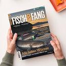 Schräg gehaltenes Angelmagazin „FISCH&FANG“ mit dem Untertitel „Das Erlebnis-Magazin für Angler“ und Logo „Fishing World + Filme!“, von zwei Händen einer nicht näher bestimmbaren Person. Das Cover zeigt einen dunklen Fisch mit grünem Köder vor Flusslandschaft sowie die Texte „Meeresangeln“, „Allein am Wasser“, „Fischküche“, „Trotting am Fluss“, „Rund ums Dekor“, „Heißes Deadbaiten“ und „Alle lieben Würmer“.