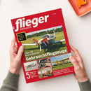 Rotes Magazin „flieger MAGAZIN“, schräg von oben fotografiert und von zwei Händen ohne erkennbare Geschlechtsmerkmale gehalten. Das Cover zeigt ein Kleinflugzeug auf einer Wiese mit „FOR SALE“-Schildern sowie weitere Flugzeug- und Cockpitfotos; lesbare Texte: „Was ein Flugzeug wirklich kostet“, „Tipps für Kauf & Betrieb“, „Gebrauchtflugzeuge“, „5 Flugzeug-Porträts: Cessna, Piper & Co.“ und „Einsteiger-Gebrauchte · Haltergemeinschaft · UL-Geheimtipps · Finanzierung“.