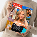 Eine Person in beigefarbenem Strickpullover hält ein schräg abgebildetes Magazin mit rotem „Gala“-Logo und blauem Rand. Das Cover zeigt Jennifer Aniston im schwarzen Kleid sowie Fotos von Victoria und David Beckham, Phil Collins und seinem Sohn, Ariana Grande und Jennifer Aniston mit Jim Curtis; sichtbare Texte: „Traut sie sich?“, „Endlich Frieden?“, „Sein Sohn kickt in Bayern“, „Große Sorge“ und „Leah Isadora Norway-Royal startet bei ‚Let’s Dance‘“.