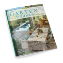 Schräg fotografiertes, einzelnes Magazin „GARTEN WOHNEN Träume“ mit grünem Einband vor schwarzem Hintergrund. Das Cover zeigt eine begrünte Terrasse mit blauem Pool, Holzboden, gedecktem Esstisch, Korbstühlen, Pflanzen und einem Wohnbereich; sichtbar sind außerdem die Texte „Genießen wie im sonnigen Süden“, „Eine helle Freude“, „Verliebt in die Provence“ und „Quell der Inspiration“.