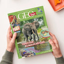 Schräg gehaltene grüne GEOlino-Zeitschrift mit Elefantenfoto im Wasser, männlicher Person mit Trommel und Satellitenillustration; zwei Hände halten das Heft. Lesbare Texte: „Die Welt für junge Entdeckerinnen und Entdecker“, „SATELLITEN“, „TIERISCHE KLIMASCHÜTZER“, „Checker Tobi“, „Was Waldelefanten, Biber und Wale für die Umwelt tun“ und „GEOlino unterstützt UNICEF“.