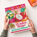 Schräg gehaltene Zeitschrift „Good Health“ mit pink-grünem Cover, in zwei Händen vor hellem Hintergrund. Sichtbar sind eine Frau im Freien, ganze und aufgeschnittene Drachenfrucht sowie Sanddorn; Texte: „Endlich schmerzfrei!“, „Japan-Workout – Fit in nur 3 Minuten“, „12 Jahre länger gesund leben“ und „Kraftpaket Brokkoli“.