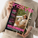 Schwarzes „InStyle“-Zeitschriftencover mit pinkfarbener Typografie, gehalten von einer Person im beigefarbenen Strickpullover; das Gesicht ist nicht sichtbar. Das Cover zeigt eine Frau im hellen Outfit vor einem Fenster sowie die Texte „TREND-SHOES“, „Micro Track-Shorts – im Herbst?!“, „LESLIE MANN“, „SKIN-TONE HAIR“ und „NEUE MODE“.