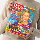 Weibliche Person im beigefarbenen Strickpullover hält ein schräg abgebildetes Magazin mit dem Titel „Paula“ und dem Schriftzug „Rätsel Gewinne Spaß“. Das farbige Cover zeigt eine blonde Frau, Kuchen, ein Gericht, ein rotes Auto, einen Grill und eine Landschaft; sichtbar sind außerdem „Gratis XXL-Rätselteil“, „Sofort-Hilfe für starke Muskeln“ und „Neues Drama“.