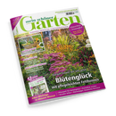 Schräg dargestelltes, weißes Gartenmagazin „mein schöner Garten“ vor schwarzem Hintergrund mit glänzendem Cover und großem Gartenfoto voller grüner Pflanzen, violetter Blüten und gelber Blumen. Sichtbare Texte: „Europas größtes Gartenmagazin“, „Zucchini & Kürbis – Vom Beet auf den Tisch“, „Grüne Schätze entdecken“, „Blütenglück mit pflegeleichten Fetthennen“ sowie „Klima­schutz + Artenvielfalt“.