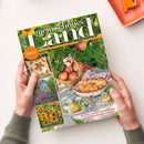 Zeitschrift „mein schönes land“ mit grünem Naturmotiv, Äpfeln, Apfelkorb, Apfelkuchen und Gartenbildern, gehalten von zwei Händen. Sichtbare Texte: „Gutes bewahren · Schönes entdecken · September · Oktober 2026“, „30 Seiten kreativ durch den Herbst“, „Bunter Blütenzauber im Landhausgarten“, „Sonnenbraut pflanzen, kombinieren & pflegen“ und „Geschenke der Natur“.