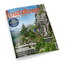 Schräg abgebildetes Magazincover „outdoor“ mit orangefarbenem Schriftzug und dem Untertitel „WANDERN. REISEN. ABENTEUER.“ vor einer alpinen Landschaft mit Felsen, Wald und blauem Himmel. Eine männliche Person und ein Kind wandern am Fels; sichtbare Texte lauten „Traumhafte Alpen“, „Japans Wanderjuwel“ und „Rucksäcke“.