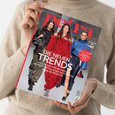 Eine Person im beigefarbenen Strickpullover hält eine schräg fotografierte Zeitschrift mit dem Titel „Petra“ und dem Text „Mein Leben! Mein Luxus!“. Auf dem Cover sind drei weibliche Models in schwarzer, roter und blauer Kleidung sowie die Aufschriften „Die neuen Trends“, „Stylische Frisuren … und welche zu Ihnen passt“, „Bretonische Geheimnisse“ und „Premium-Heft“ erkennbar.